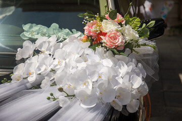 Elegant floral decoration adorning a car for a wedding celebration in a sunny outdoor setting