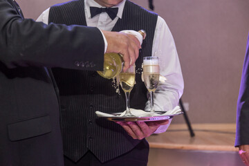 Elegant service at a celebration as a waiter pours sparkling wine into crystal glasses