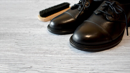 Polished Black Shoes with Brush on Wooden Floor