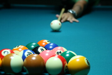 Skillful player lines up shot in vibrant pool hall during evening match with well-arranged billiard balls