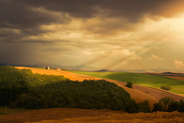 Moody golden hour over Italian countryside with dramatic light and rolling fields