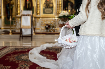 Charming floral basket held by a young girl during a beautiful wedding ceremony in an ornate church setting