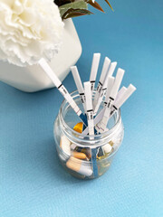 Clear Glass Jar with Colorful Vitamins and Capsules for Daily Supplementation on a Blue Background
