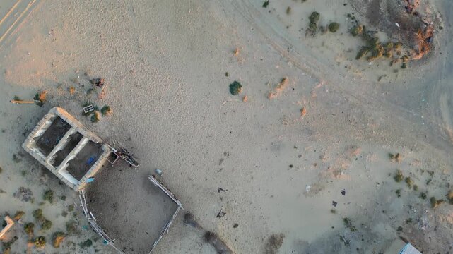 Top-down view of the ruined Akespe village buried in desert sand. Once near the Aral Sea, now only rooftops and sand-covered walls remain. Evening sunlight.
