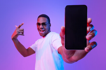 Cool Mobile Offer. Excited African Guy Demonstrating Smartphone With Black Screen, Standing Under...
