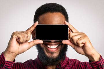 Look At This App. Black Guy With Smartphone Posing, Holding Phone Screen In Front Of Face Standing...