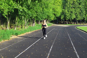Adult European Woman in Black Running in Open Stadium.