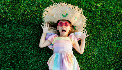 little girl in hat lying on grass resting in park