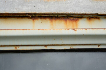 Close-up of a rusty metal edge and frame revealing deterioration and corrosion next to a glass...