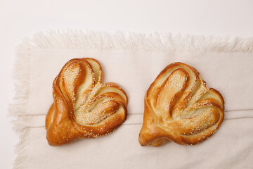 Heart-shaped sweet buns with sesame seeds, homemade pastry, golden baked bread, soft fluffy texture, romantic bakery treat, holiday dessert, rustic wooden table background, close up, cozy food photogr