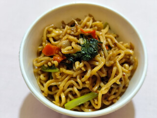 Chewy instant fried noodles in a white bowl, highlighting its texture and deliciousness, against a blurry bowl background.