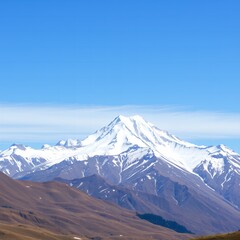 Fototapeta premium Majestic snow capped mountain peak under a clear bright blue sky with wispy clouds