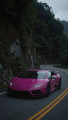 Naklejka premium Pink Huracan sports car in motion on winding road. Car sleek design contrasts with forested mountainous landscape. Side angle view provides unique perspective on speed, trajectory. Luxury sports car