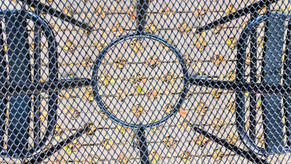 The textured background of a small table and chairs for a cafe in a weather-resistant public park is made of iron. Durable, comfortable, and ideal for outdoor public spaces, or recreation areas.