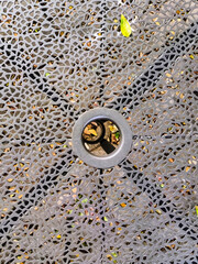 A weather-resistant, textured background for a small cafe table in a public park, made of iron. Durable, comfortable, and ideal for outdoor public spaces, parks, sidewalks, or recreational areas.