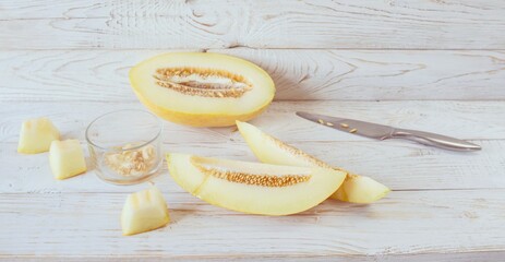 Cut ripe melon. Melon and knife on white wooden background. Top view. Beautiful still life.