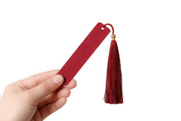 Hand holding a red bookmark with a tassel.