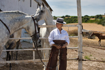 A young, beautiful Spanish woman dressed in riding clothes and wearing a traditional Spanish hat...