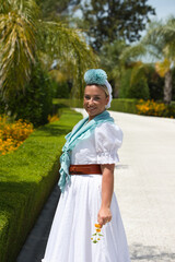A beautiful young Spanish woman dressed in a traditional white Andalusian flamenco dress with a...