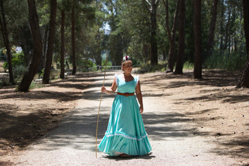 A beautiful young Spanish woman dressed in a traditional green flamenco dress and with a flower in...
