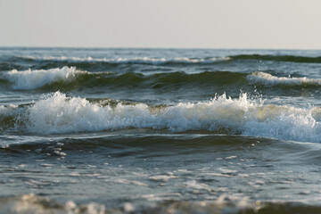 Sea waves splashing lit by sun, dramatic photo.  Realistic photo, high resolution, water background