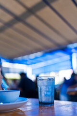 A clear glass with ice cubes and water sits on table dinner