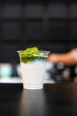 A glass of iced matcha latte in clear glasses, with two layers of green tea and fresh milk, accented by ice cubes. The close-up emphasizes the refreshing texture and color