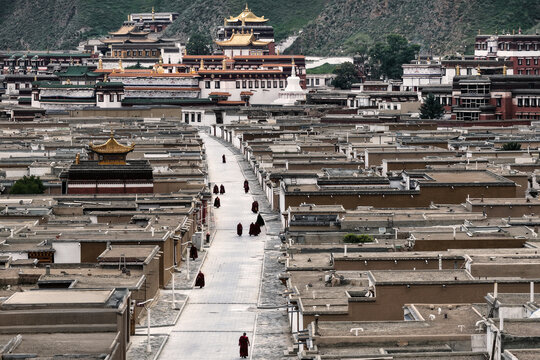 Aerial view of the expansive rooftops stretching towards the distant Labrang Monastery under the clear sky, Xiahe, Gansu, China.