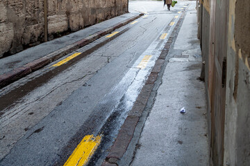 Calle estrecha de una ciudad después de la lluvia con un peatón al fondo