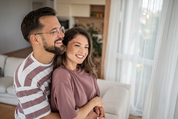 Fototapeta premium Happy couple embracing and smiling in modern apartment