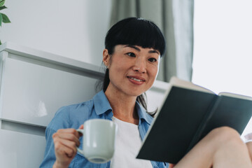 Japanese woman drinking coffee and reading a book at home