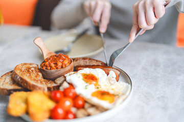 Eating english breakfast menu on marble table with tea fried eggs baked beans in tomato sauce and grilled bacon sausage tasty meal
