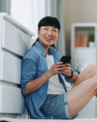Happy woman using smart phone at home, relaxing and browsing internet