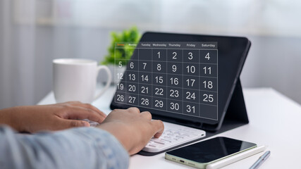 Organized person planning schedule with digital calendar app on tablet, with smartphone, keyboard,...
