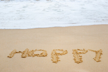 Inscription happy and incoming sea wave on sand at beach. Concept of travel and vacation time
