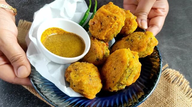 Bengali-style kakrol-er pur bhaja &ndash; stuffed spiny gourd fry, traditional Indian vegetarian snack, crispy kakrol fritters being cooked and served
