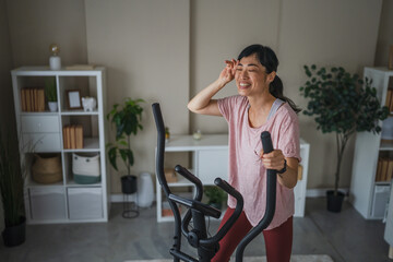 Tired japanese woman exercise on static bike at home