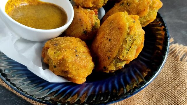 Bengali-style kakrol-er pur bhaja &ndash; stuffed spiny gourd fry, traditional Indian vegetarian snack, crispy kakrol fritters being cooked and served
