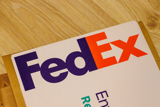 Warsaw, Poland - August 2, 2025: Close-up of a FedEx envelope lying on a wooden surface, showcasing the iconic FedEx logo with vibrant colors that represent reliability.