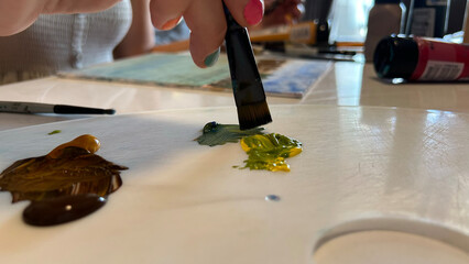 A close-up of a female painter demonstrating her craftsmanship as she works on a canvas with various colors of paint and brushes