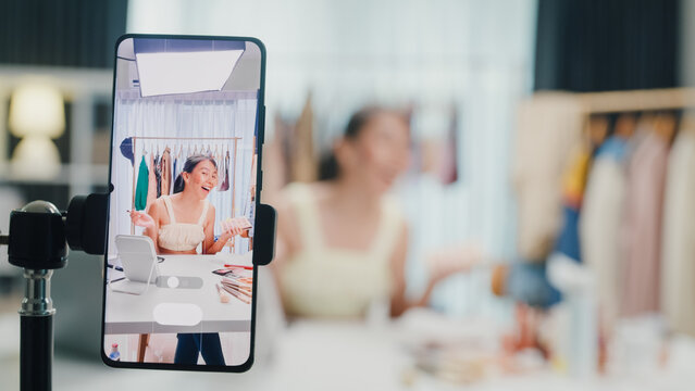 Close-up phone screen recording Asia lady vlogger look phone camera apply eye shadow palette on skin live sale online screen in IG story reel tiktok work at home studio. Business online media concept.