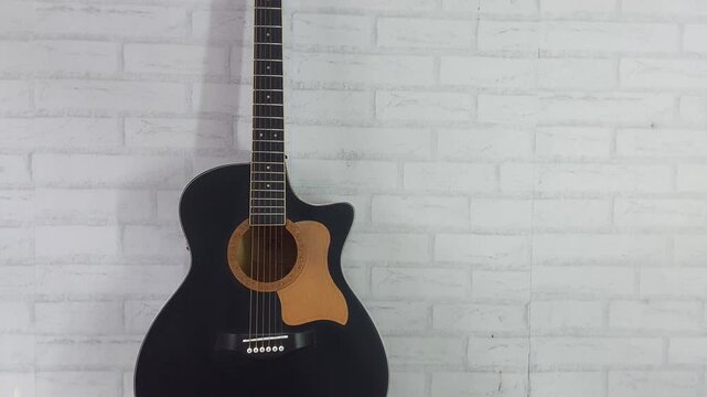 an elegant black acoustic guitar made of rosewood, with six steel strings that produce a melodious sound.
