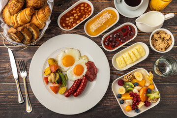 Traditional English breakfast with eggs, beans, sausage, and fresh fruits