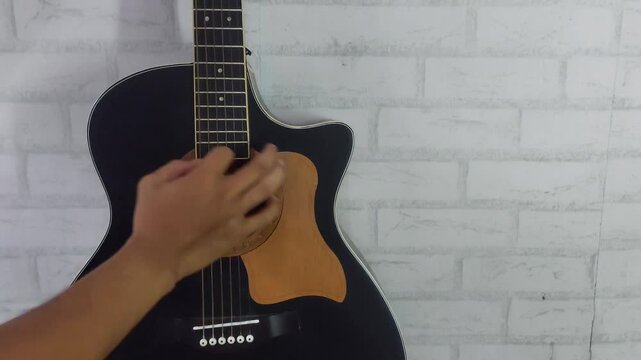 an elegant black acoustic guitar made of rosewood, with six steel strings that produce a melodious sound.