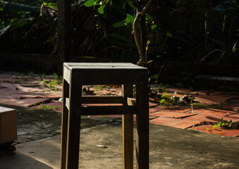 An old wooden stool in a garden backyard under the sunlight. Concept of nostalgia, peace, and rural...