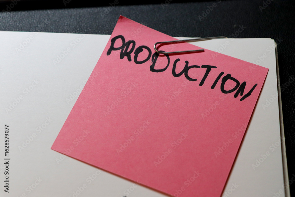 Poster a pink sticky note labeled production is attached to a blank paper using a paperclip, symbolizing or