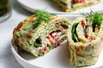 Appetizing zucchini roll with tomatoes and garlic on a light background