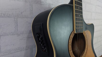 an elegant black acoustic guitar made of rosewood, with six steel strings that produce a melodious sound.