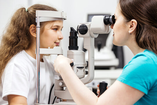 Young girl undergoing eye examination with ophthalmologist using slit lamp in a bright clinical setting, showcasing the importance of pediatric eye care and vision health awareness