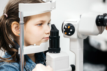 Young girl undergoing eye examination using advanced ophthalmic equipment, focused on the...